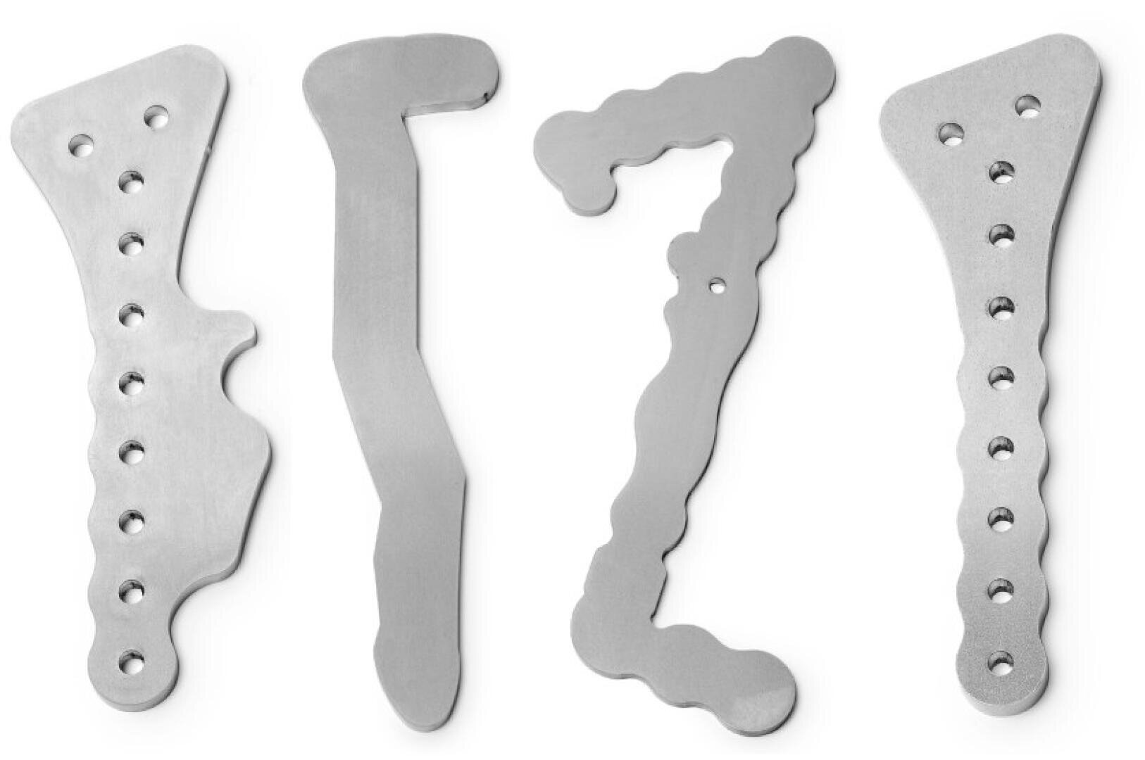 Vier verschiedene orthopädische Knochenplatten aus Metall, jede mit mehreren Schraubenlöchern und einzigartigen Formen, sind vertikal vor einem weißen Hintergrund angeordnet.