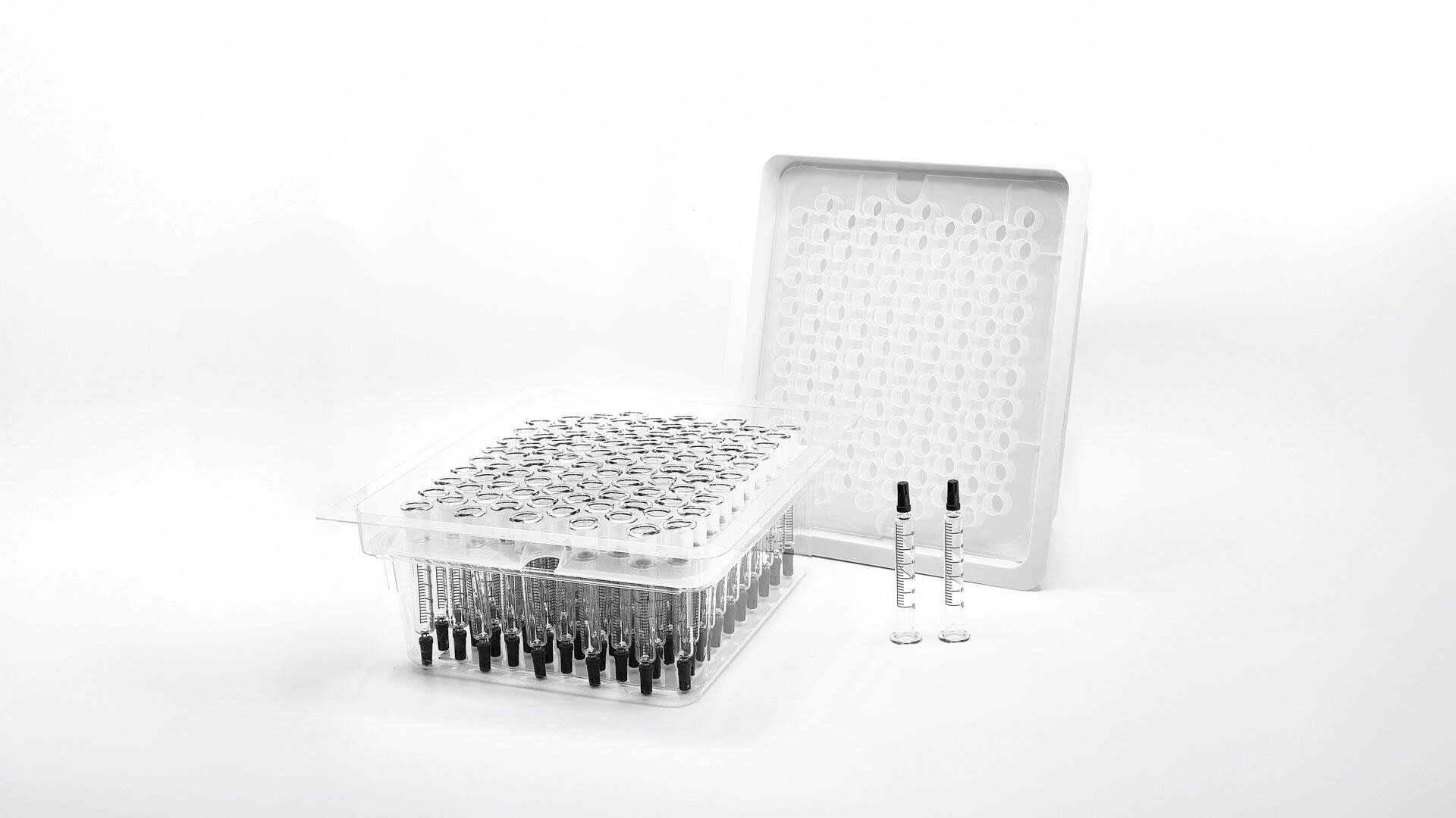 Auf einer durchsichtigen Kunststoffschale befinden sich mehrere Spritzen mit schwarzen Kolben. Eine identische Schale lehnt aufrecht dahinter. Zwei einzelne Spritzen liegen davor auf einem schlichten weißen Hintergrund.