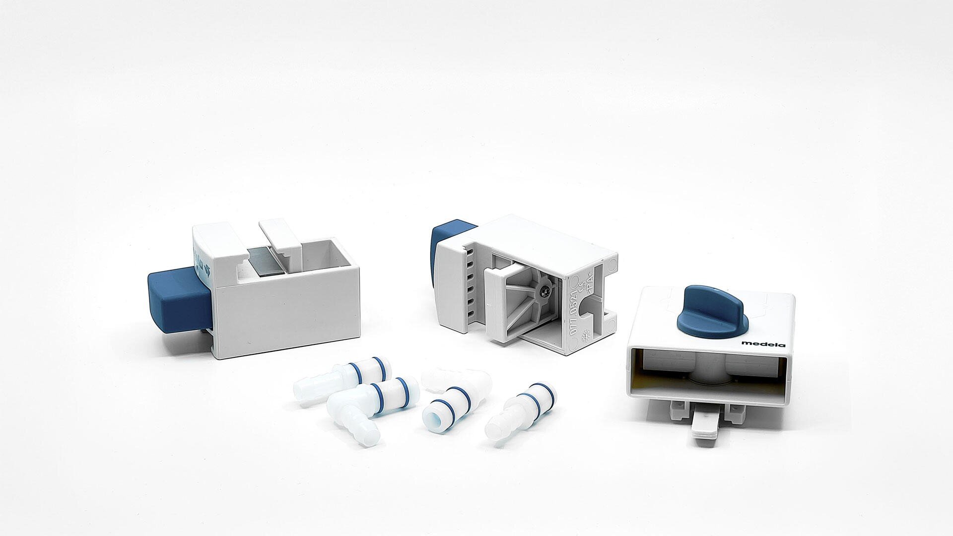 Three white and blue plastic medical or laboratory devices are shown alongside four small white and blue connectors, all placed on a plain white background.