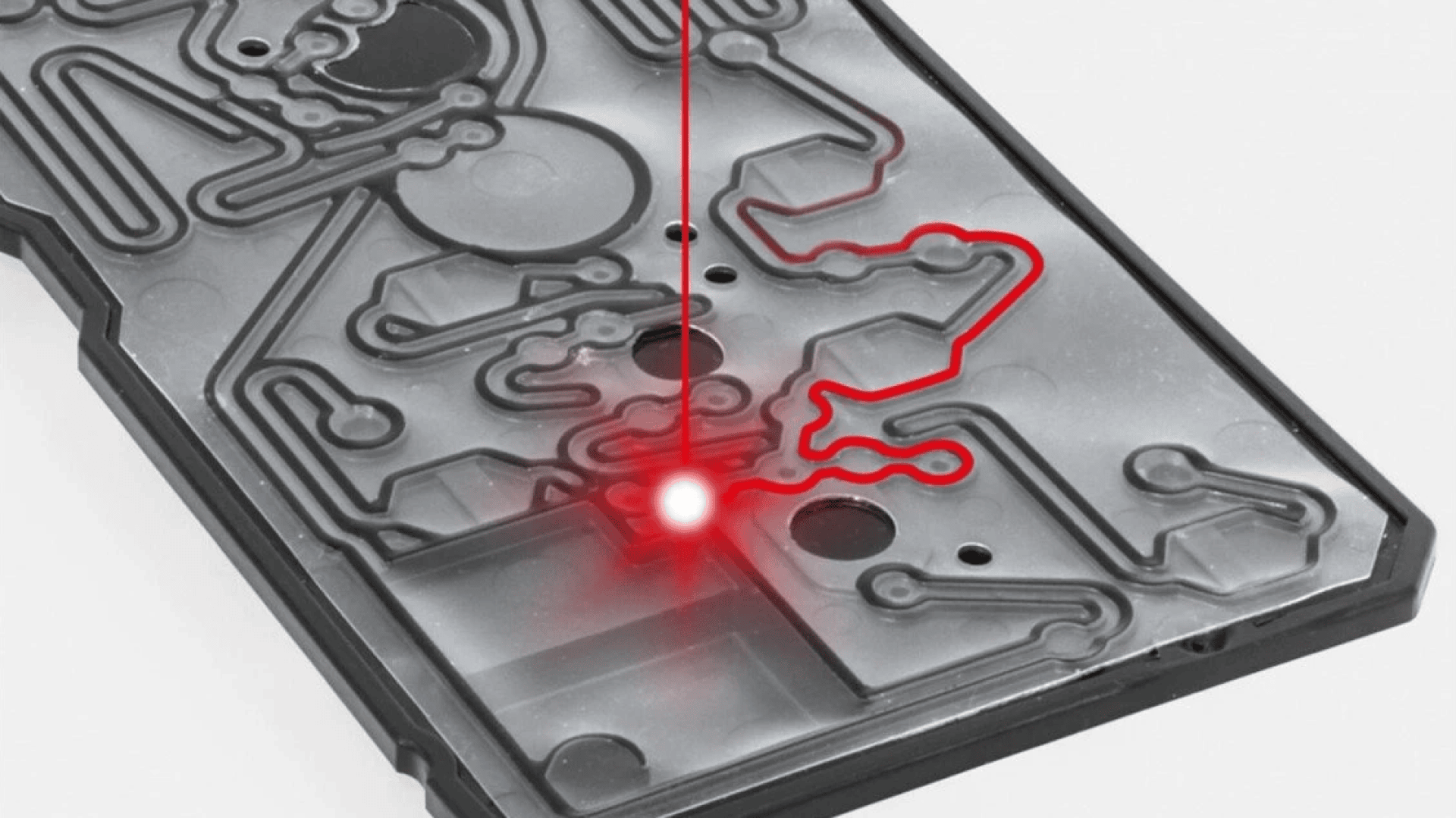 A close-up of a circuit board with a red laser tracing a complex path along its surface, highlighting the circuitry and connection points.