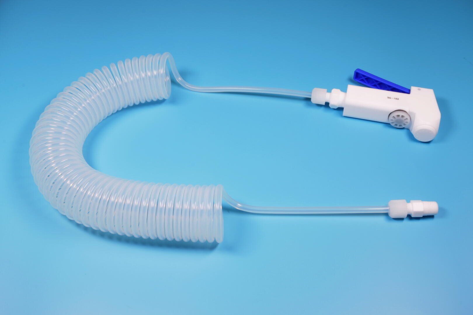 Ein weißer und blauer medizinischer Sprühkopf, verbunden mit einem langen, gewundenen, klaren Kunststoffschlauch auf hellblauem Hintergrund.