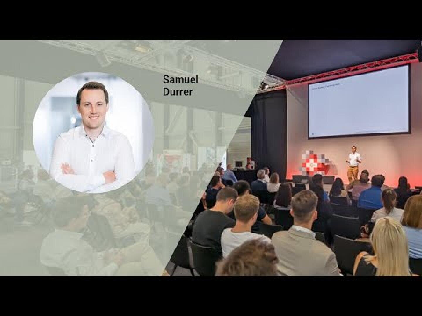 Ein Mann präsentiert auf der Bühne vor einem Publikum in einem modernen Veranstaltungsraum. Auf der linken Seite zeigt ein transluzentes Overlay ein Porträt des Redners mit der Aufschrift Samuel Durrer, der die Arme verschränkt und lächelt.