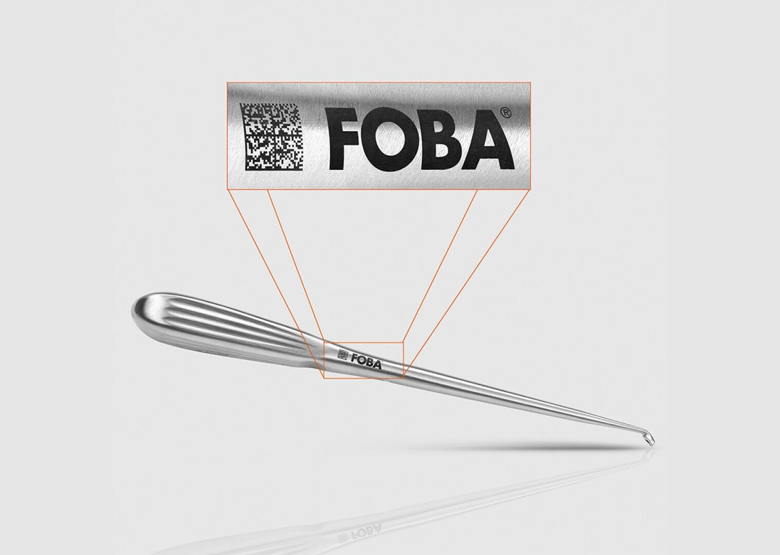 A metal surgical instrument with an engraved label, FOBA and a QR code, magnified to highlight the detailed laser marking on the surface of the instrument.