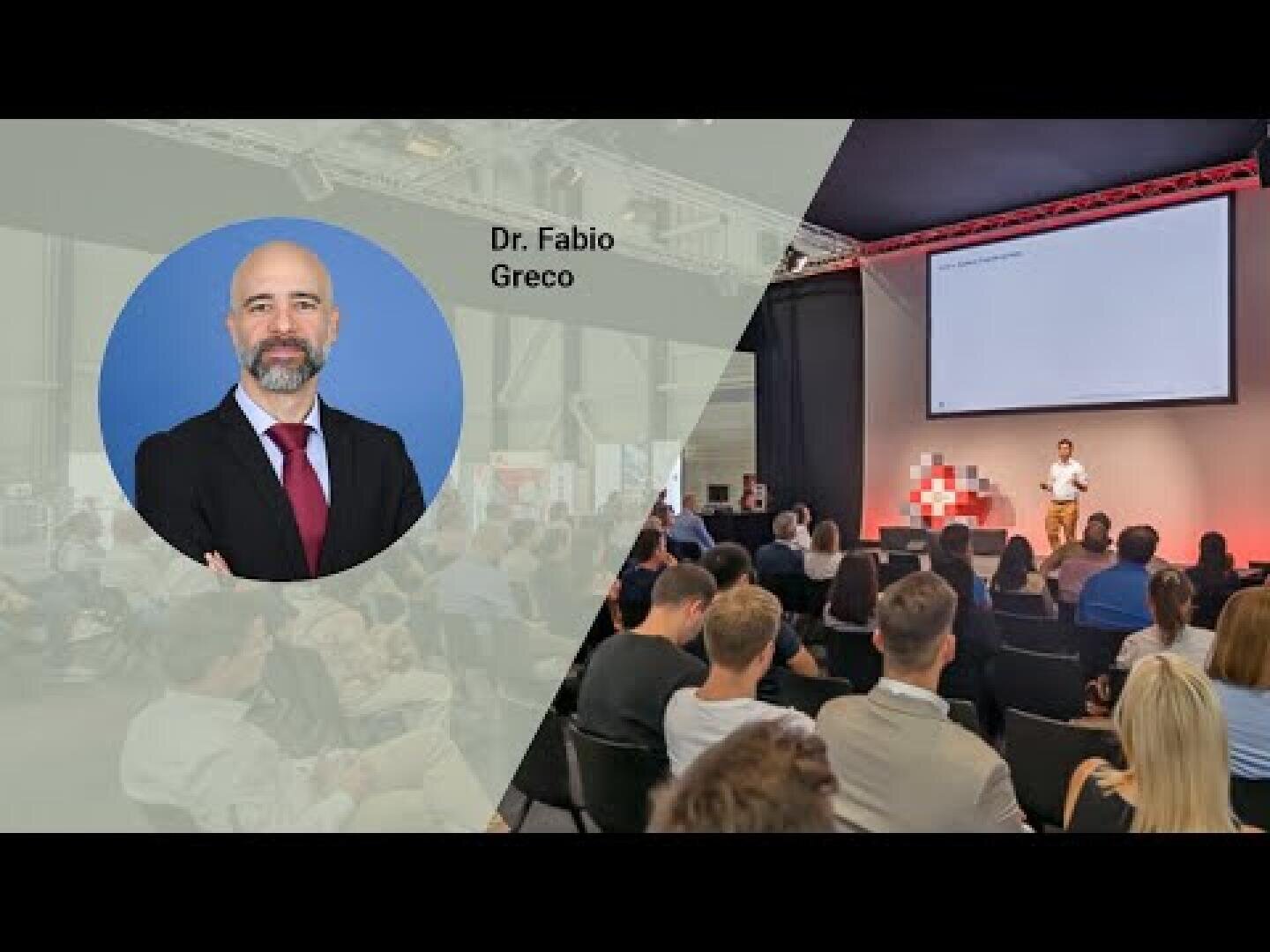 Ein Konferenzraum mit Zuhörern, die einem Redner auf der Bühne zuhören; daneben ein Kopfbild von Dr. Fabio Greco mit seinem Namen.