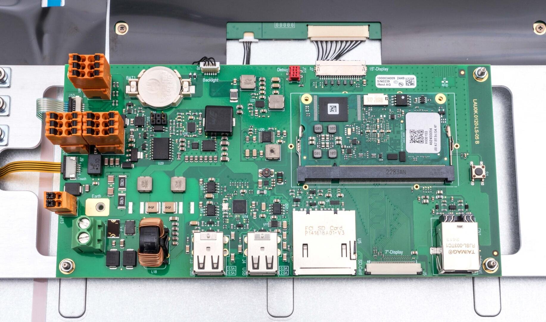 Eine Nahaufnahme einer grünen Leiterplatte mit verschiedenen elektronischen Komponenten, darunter Anschlüsse, Chips, USB-Anschlüsse und ein SD-Kartensteckplatz, montiert auf einer metallischen Oberfläche.