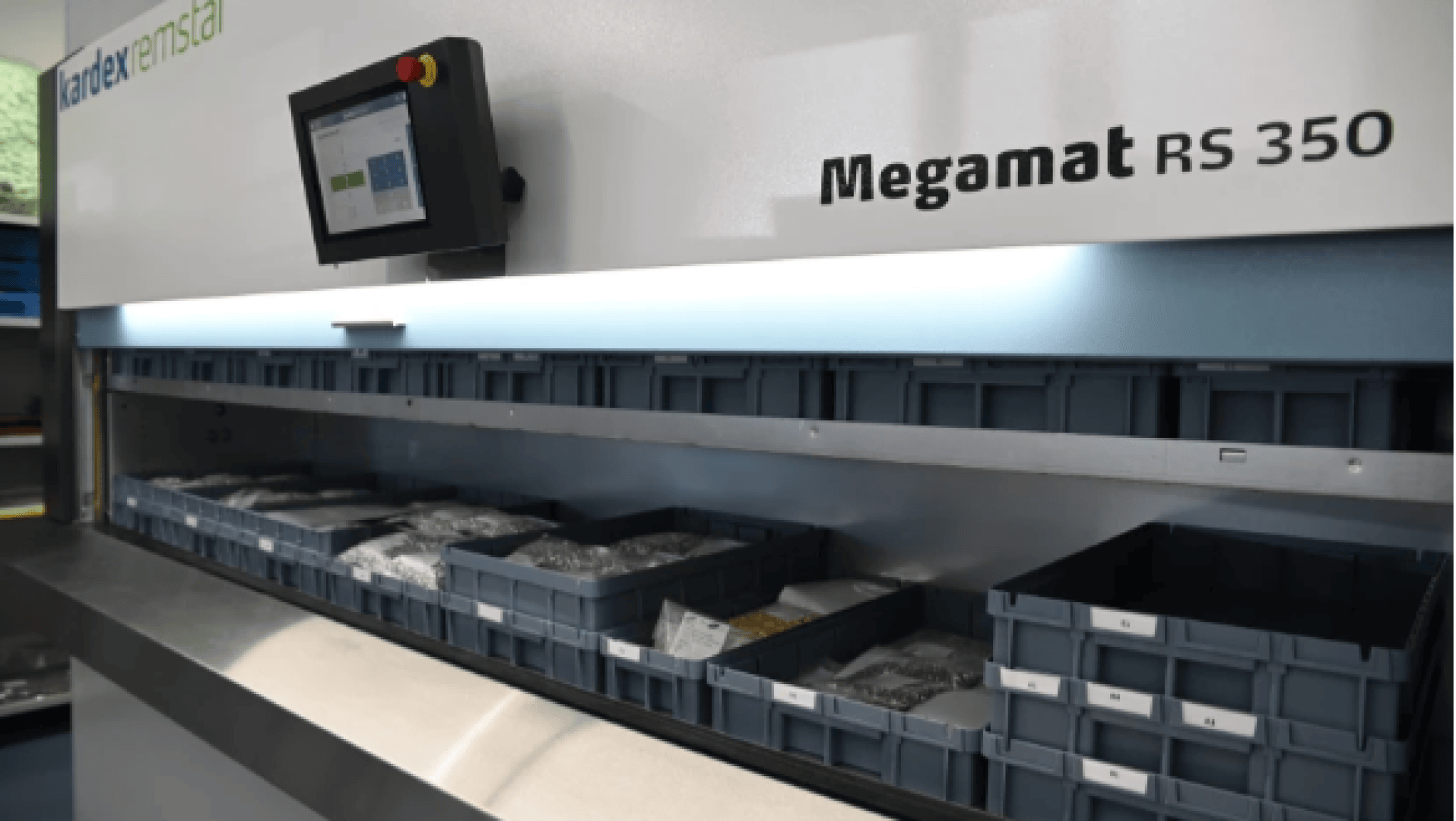Ein automatisiertes Lagersystem Kardex Remstar Megamat RS 350 mit Kleinteilebehältern in Regalen und einem Touchscreen-Bedienfeld auf der linken Seite, das die Systemoptionen anzeigt.