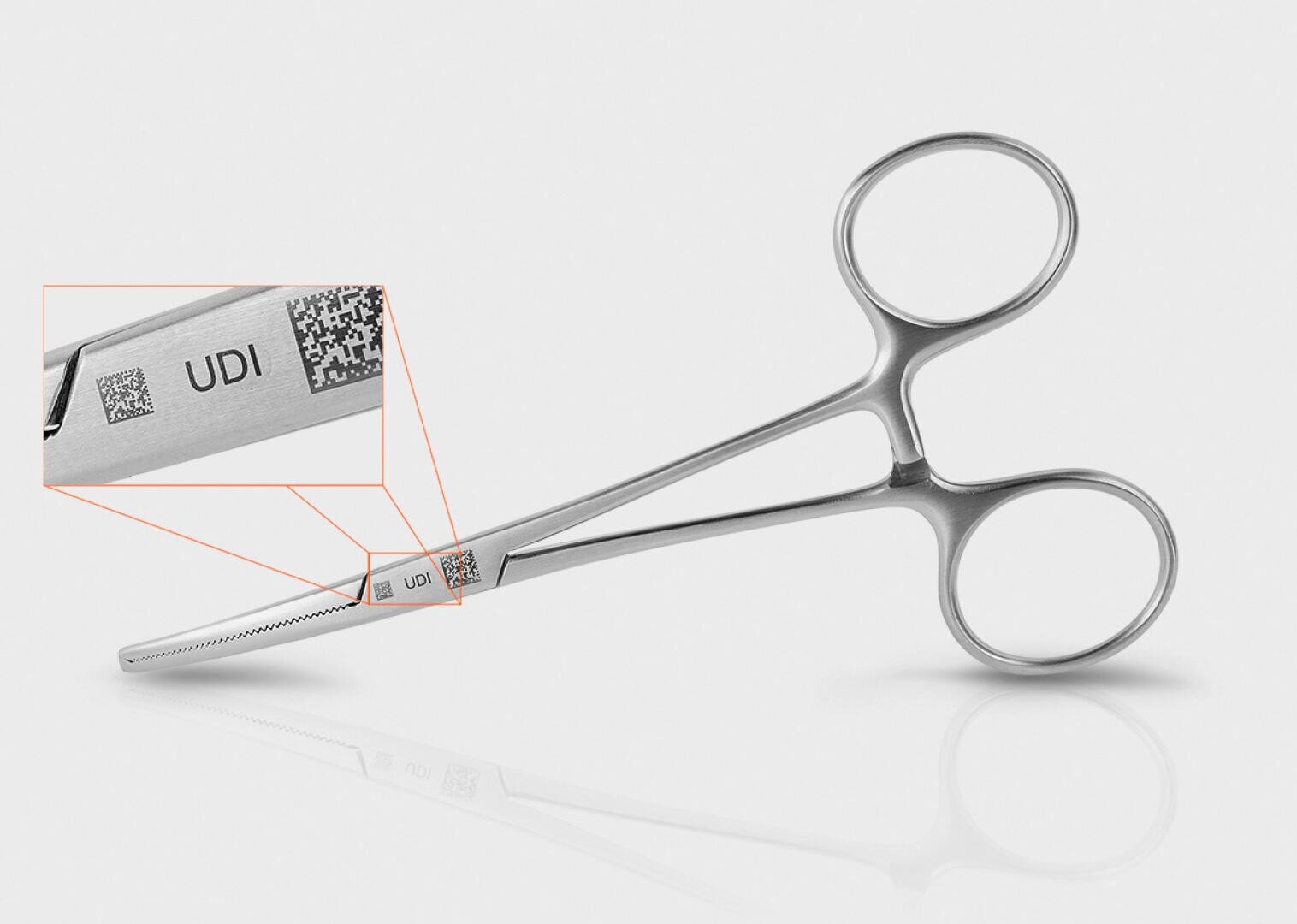 Eine chirurgische Pinzette mit einer Nahaufnahme, die einen lasergravierten QR-Code und die Buchstaben UDI auf dem Griff zeigt.