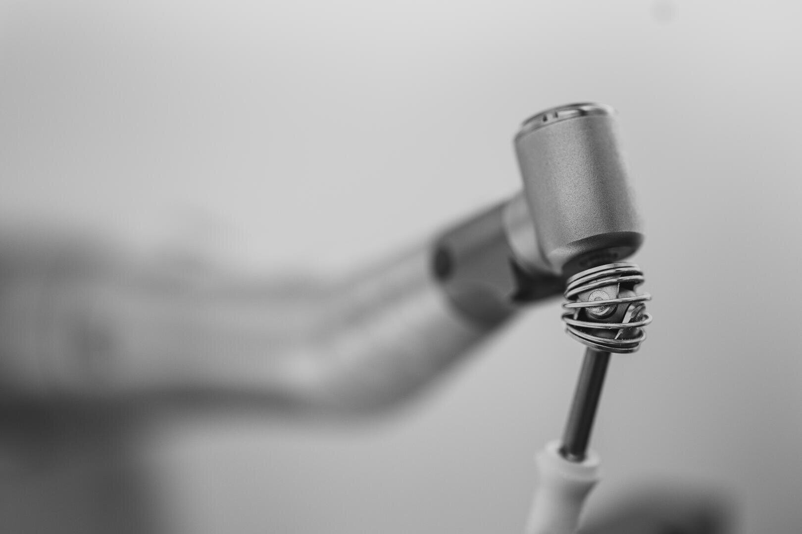Eine Nahaufnahme eines flexiblen Dentalinstruments mit einem federgestütztem Gelenk. Die metallischen Details des Bohrers sind scharf abgebildet.