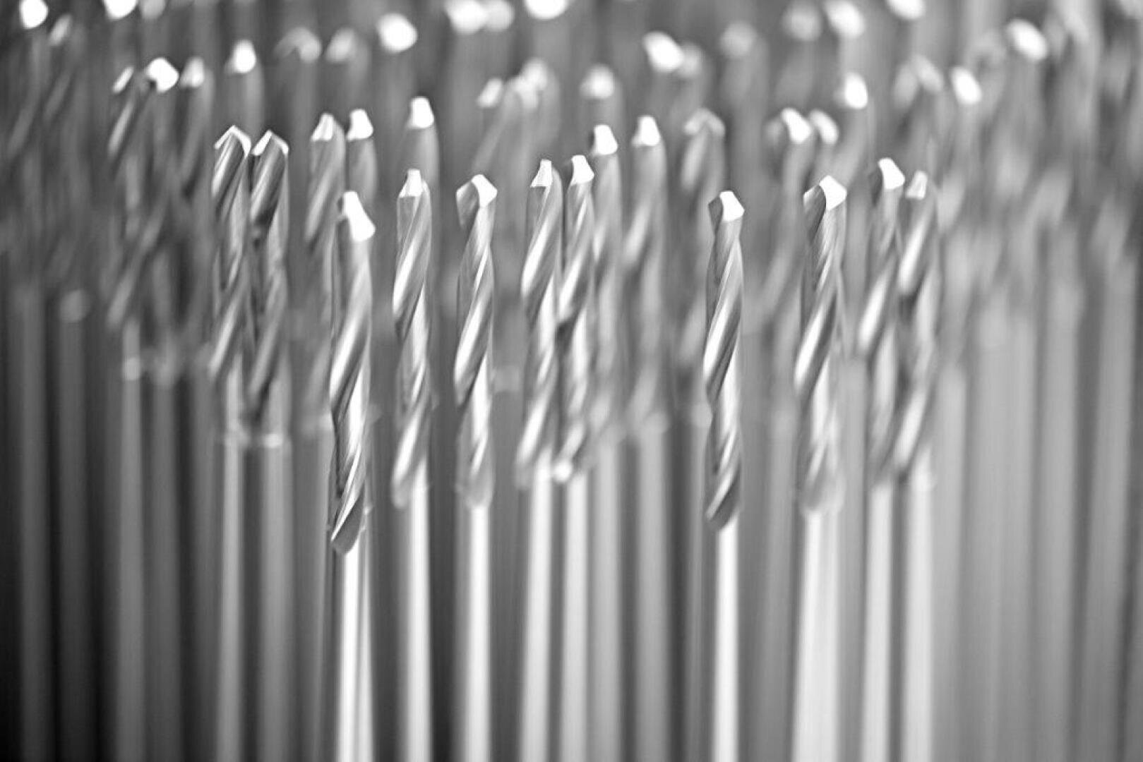 Eine Nahaufnahme von vielen Metallbohrern, die aufrecht in Reihen stehen, mit einer geringen Schärfentiefe, die einen unscharfen Hintergrundeffekt erzeugt.