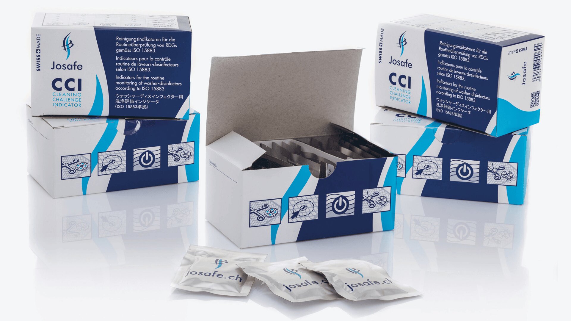 Drei blau-weiße Schachteln mit der Aufschrift Josafe CCI Cleaning Challenge Indicator sind ausgestellt, wobei eine Schachtel geöffnet ist und ihren Inhalt zeigt. Drei kleine versiegelte Päckchen sind vor den Schachteln platziert.