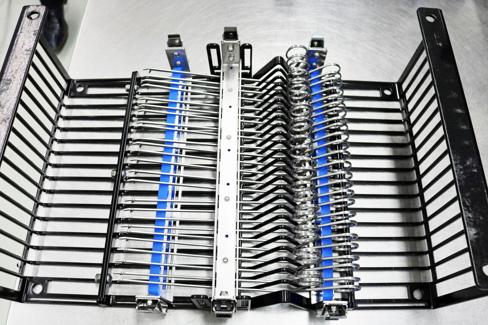 Ein Sterilisationstablett aus Metall fasst mehrere chirurgische Instrumente, einschließlich Pinzetten und Scheren, die ordentlich in Reihen auf einer Metalloberfläche angeordnet sind.