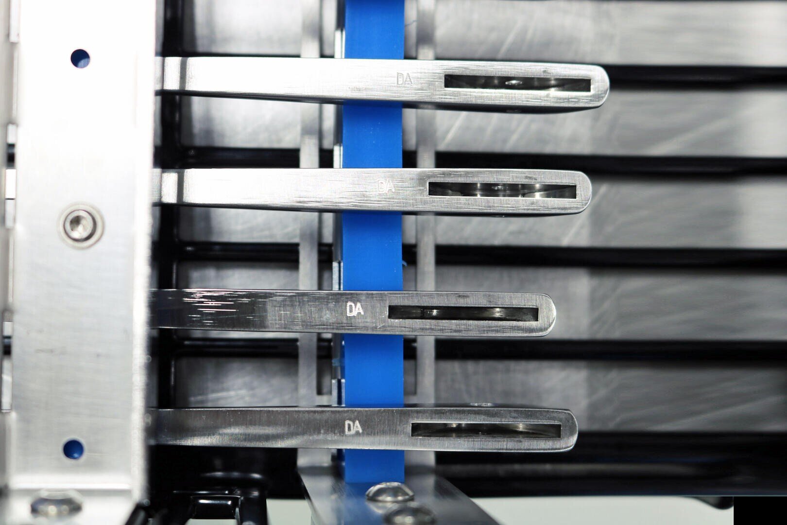 Nahaufnahme einer Metallmaschine mit drei horizontalen Hebeln, die mit DA beschriftet sind, und einem vertikalen blauen Streifen im Hintergrund, der ein glänzendes, industrielles Design aufweist.