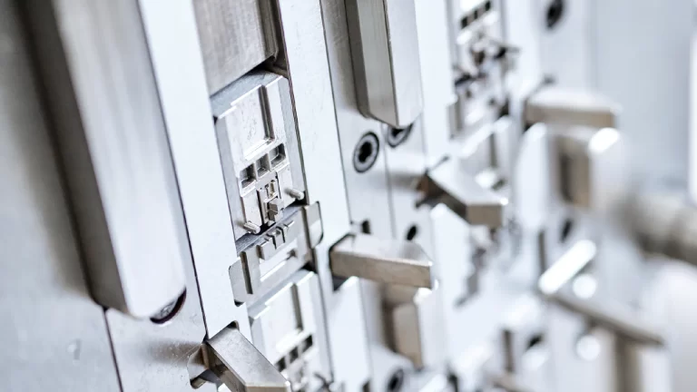 Nahaufnahme einer metallischen Industrieform mit komplexen mechanischen Teilen, Hebeln und detaillierten Komponenten, die in der Fertigung oder in feinmechanischen Prozessen verwendet werden.