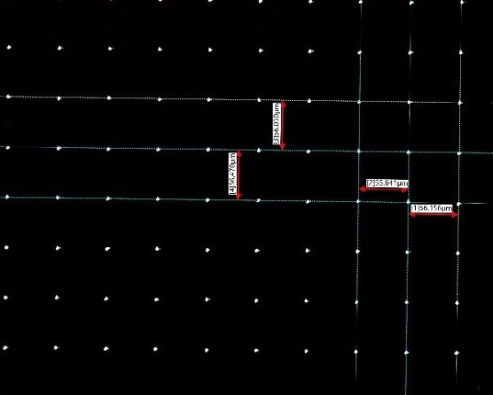 Ein Raster aus kleinen weißen Punkten auf schwarzem Hintergrund, mit sich kreuzenden horizontalen und vertikalen Linien. Mehrere rot umrandete Etiketten zeigen Messungen in Mikrometern an, darunter 244,48 µm, 235,84 µm und 156,14 µm.