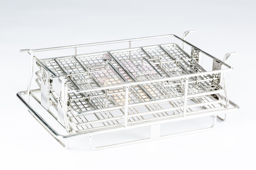 A rectangular stainless steel wire basket with a grid pattern, elevated sides, and handles, designed for holding or organizing objects, set against a plain white background.