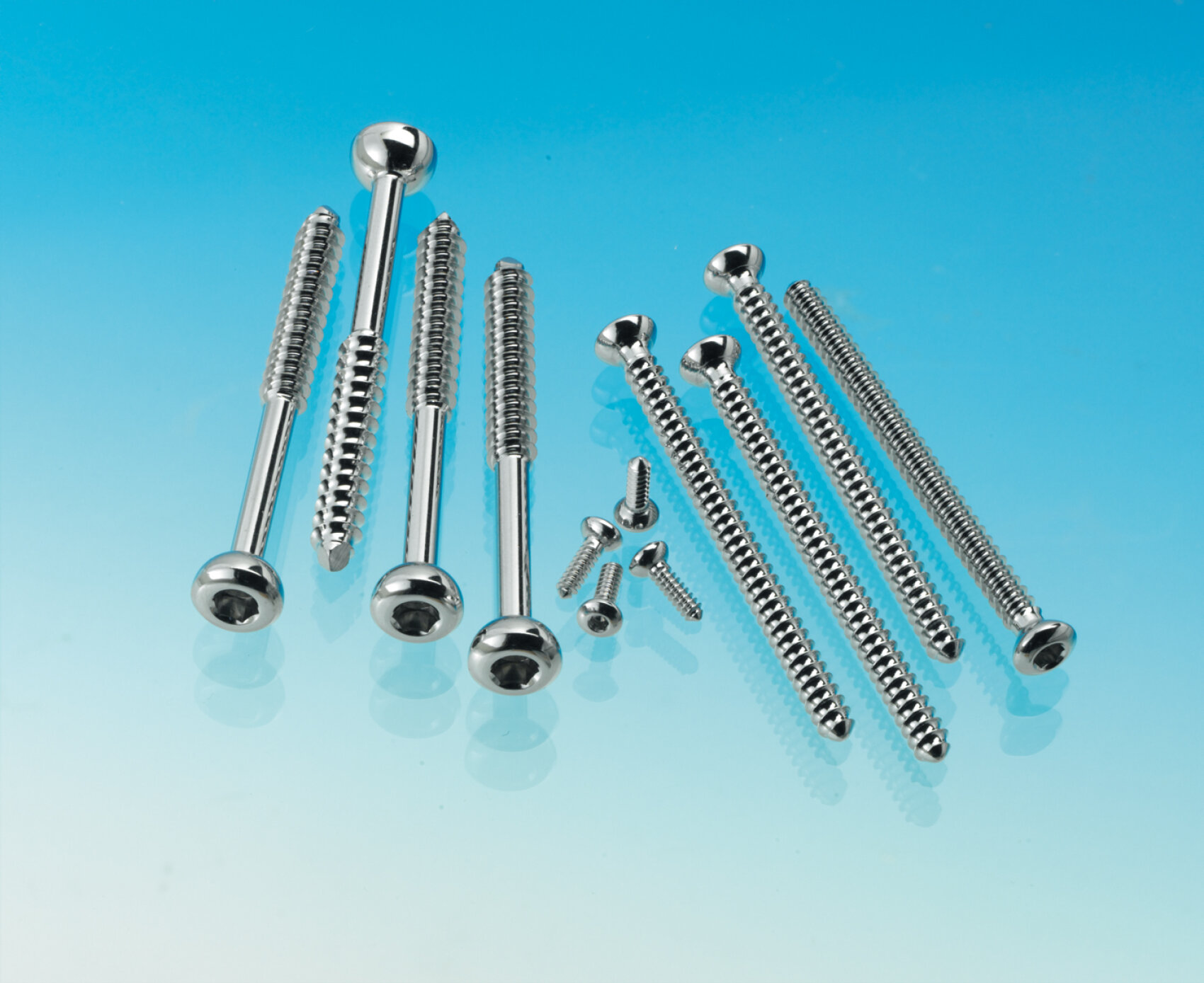 A variety of shiny metal screws arranged on a background with a blue and white color gradient. The screws vary in length and head shape, with some having a round head and others a flat or countersunk head.